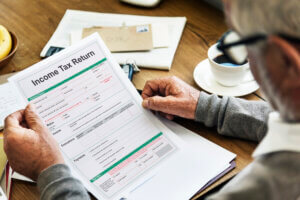 A senior citizen looking at an income tax return form, before deciding to donate to charity for a tax deduction.