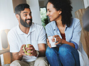 A couple sitting together with mugs of coffee, talking