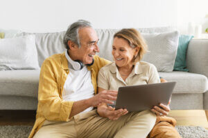 An older couple looking at a laptop together on a sofa
