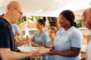 A woman volunteer serves food to people at a charity kitchen, demonstrating estate administration's community impact.