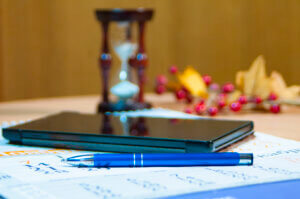 A table holding documents related to estate planning, including a pen and a clessidra (hourglass), symbolizing the importance of timing and careful planning when considering what is an estate.