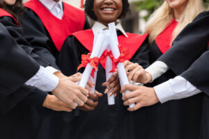 A joyful black woman wearing graduation attire holds up her degree, embodying the success of meeting "scholarship guidelines". Her achievement highlights the opportunities and accomplishments possible through educational scholarships.