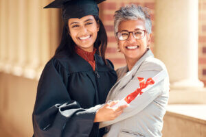 A female student, smiling broadly, embraces an older woman, both radiating joy and pride in a moment of academic achievement after getting the scholarship trusts.
