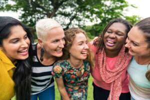 A group of women laughing and hugging each other, symbolizing the importance of charity in estate planning.