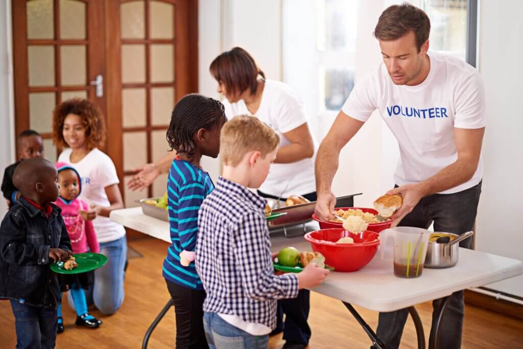 A volunteer serving a meal to a family with young children