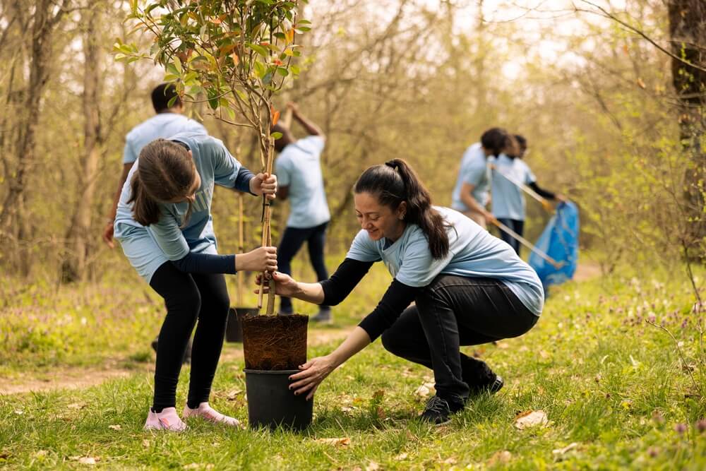 A group of volunteers planting trees and cleaning up a park, showcasing the essence of volunteerism through teamwork and environmental stewardship.
