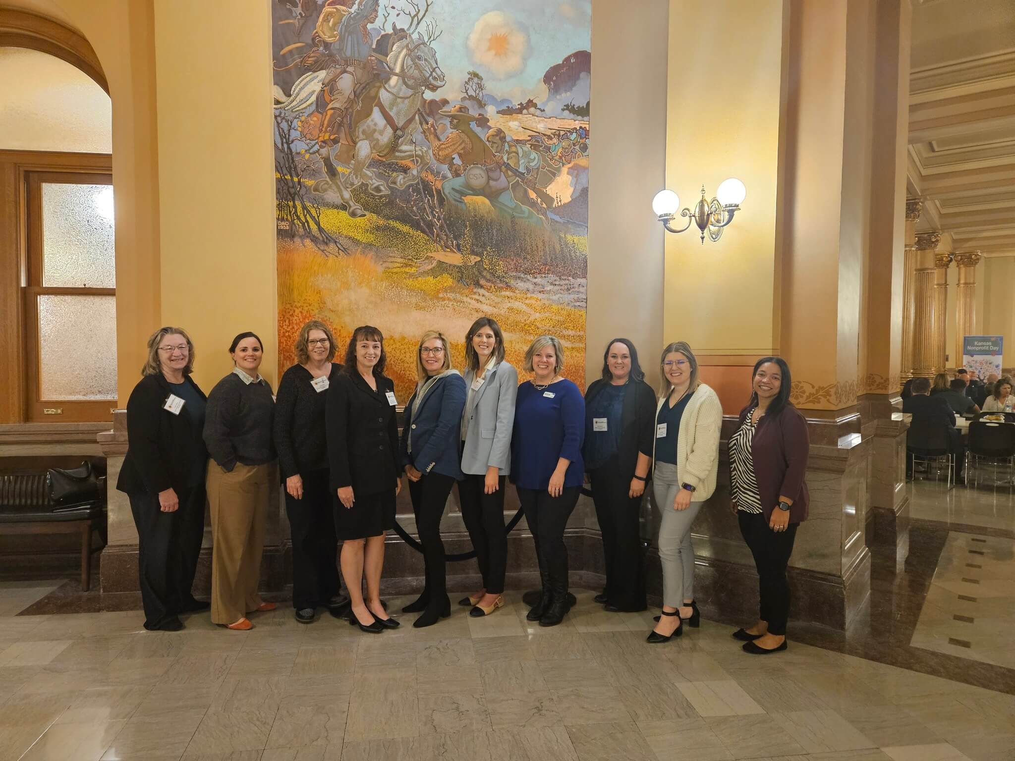 A group photograph taken indoors in front of a large mural