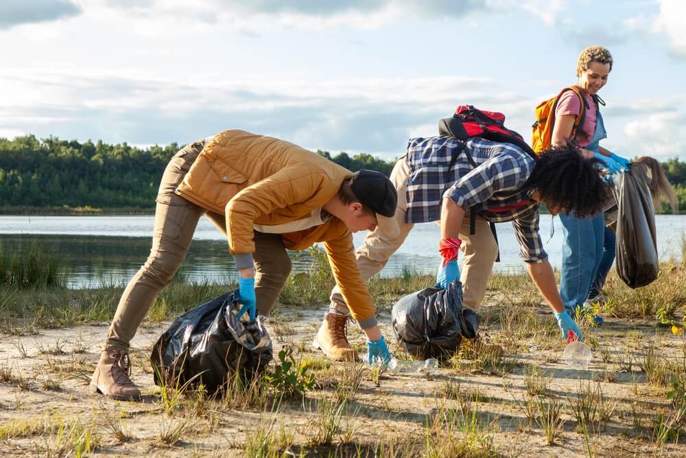 Volunteers filling trash bags during a lakeside clean-up