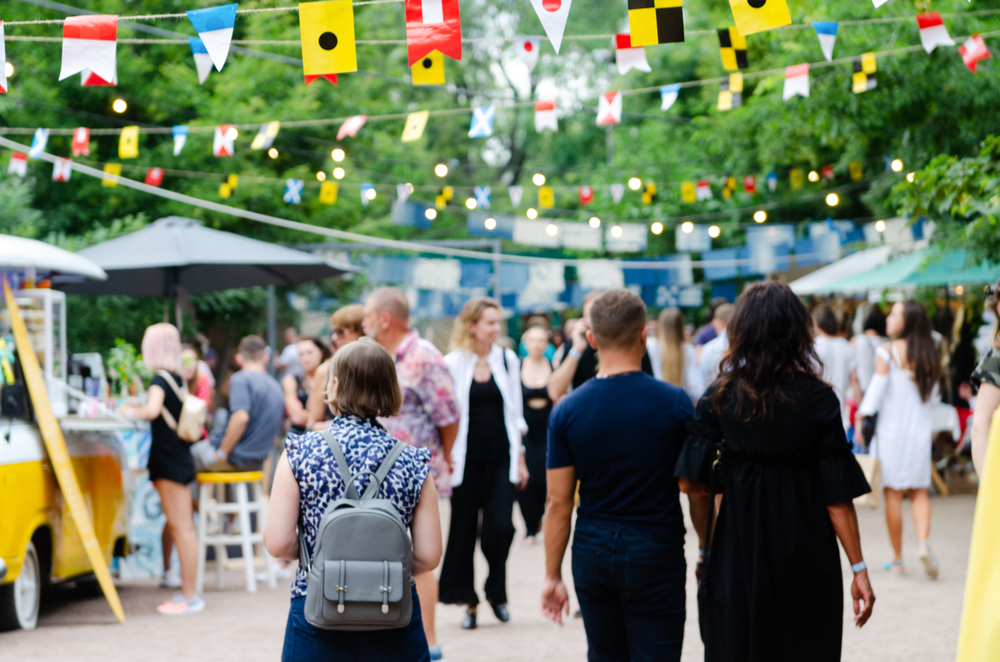 Community outdoor event with festive banners and a crowd of people, an example of how small business donations can support local events and foster neighborhood engagement.