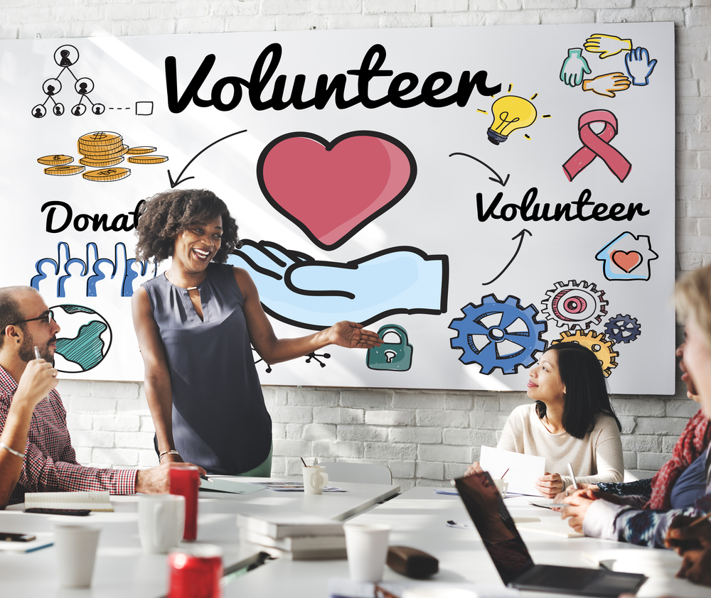 Diverse team discussing volunteer and donation strategies in a meeting room with a charity-themed board, illustrating conversations around how much should a small business donate to charity.