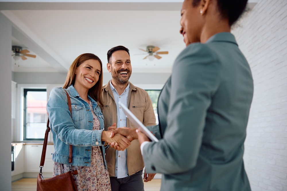 Donate land to charity concept: a couple shaking hands with a professional during a property agreement meeting, symbolizing the process of transferring land ownership for charitable purposes.