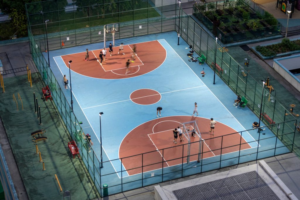 Aerial view of neighbors playing basketball on a public court, highlighting giving back to the community through donations that support shared recreational spaces.