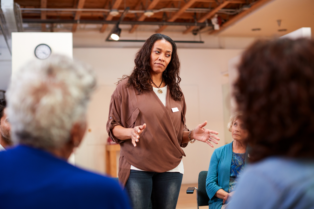 Woman speaking to a small seated group of older adults in a community room