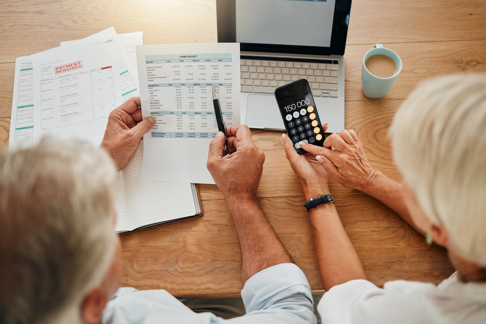 Two people reviewing budgets, bills, and financial calculations on a laptop and phone, illustrating nonprofit accounting and responsible financial management.