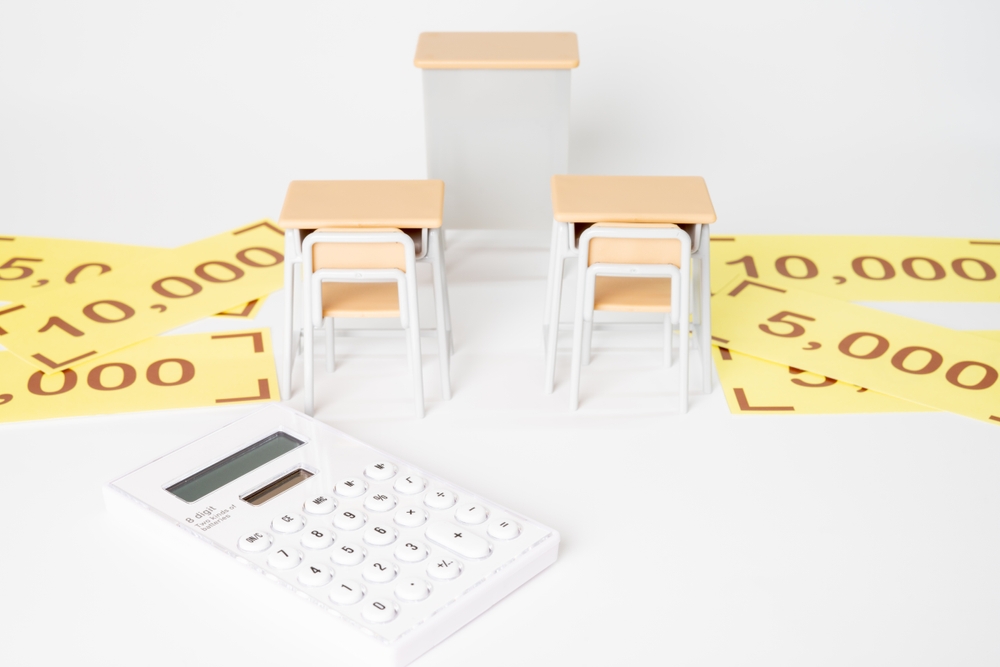 Classroom desks, scholarship amounts, and a calculator illustrating what is an endowed scholarship and education funding.