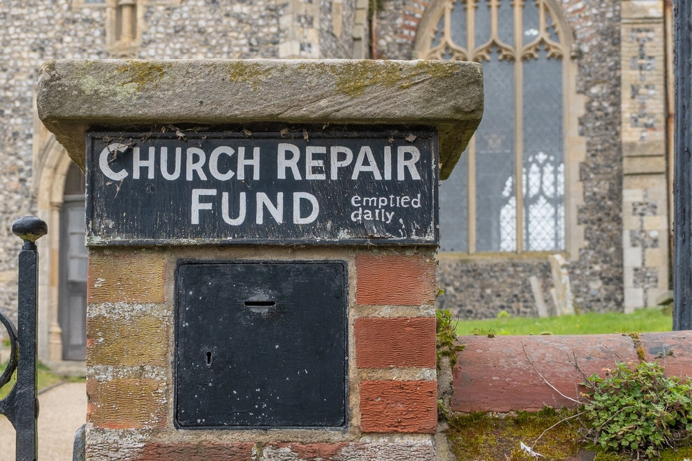 Church fundraising ideas for repairs and maintenance, featuring a traditional church repair fund donation box outside a historic stone church.