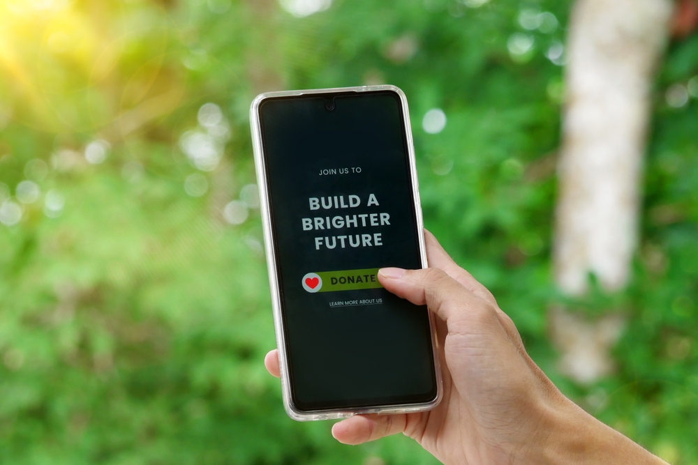 Hand holding a smartphone with an online donation page, illustrating restricted vs unrestricted donations and how donors can support specific or general nonprofit needs.