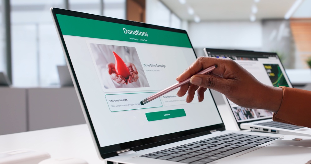 A person navigating an online donation platform on a laptop, illustrating nonprofit financial analysis and digital fundraising management.