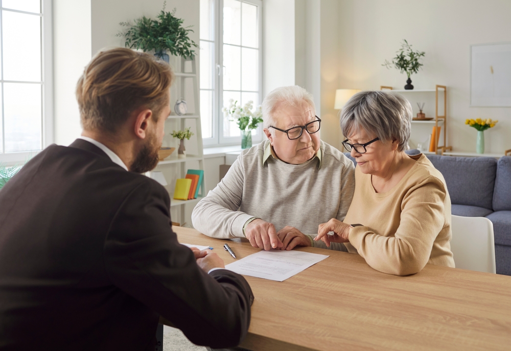 Older couple talking with an adviser across a table with papers spread between them