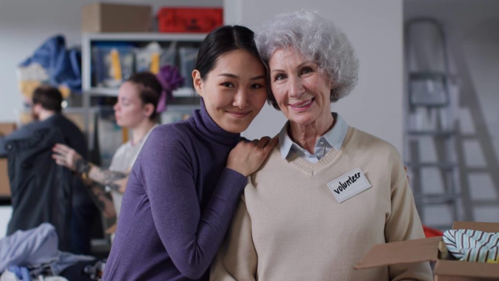 A young volunteer and an older woman smile together at a community donation center, the kind of lasting relationship donor stewardship builds.